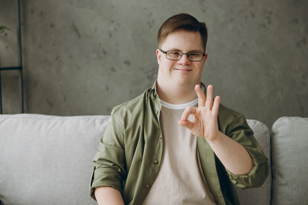 portrait of a disabled boy with down syndrome sitting on sofa