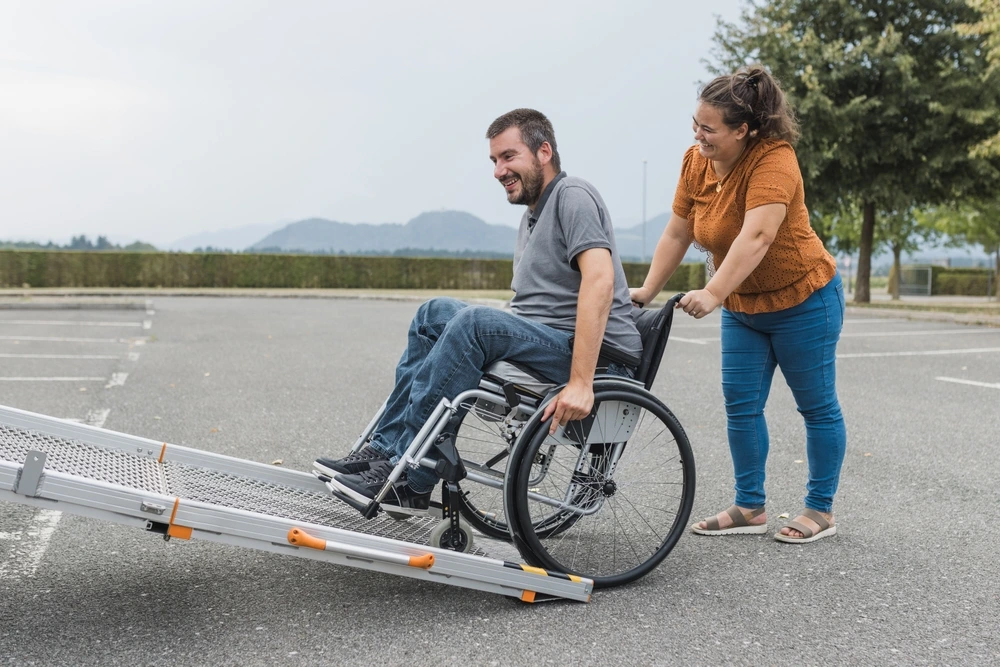 women helping a disabled men on wheelchair to get on a van